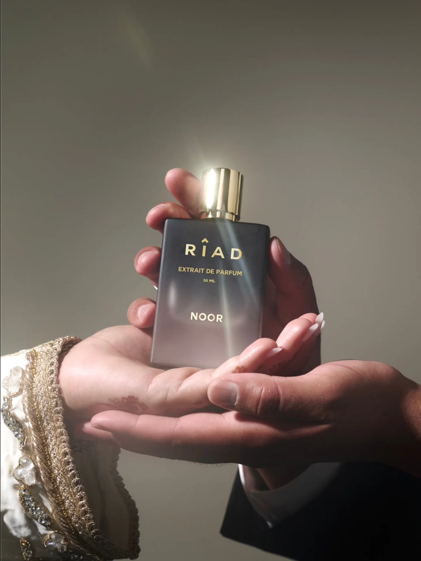 Hand med henna håller upp Riads Noor i mjukt ljus, ur Noor-kampanjen
